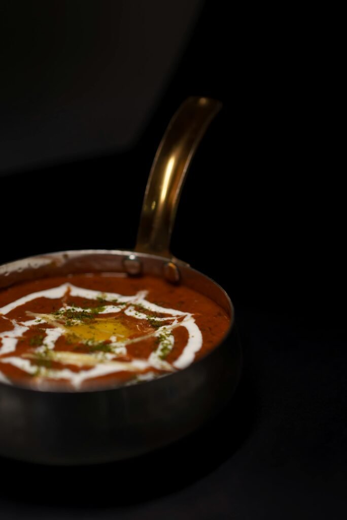 Authentic Indian dal makhani garnished with cream in a traditional brass bowl.