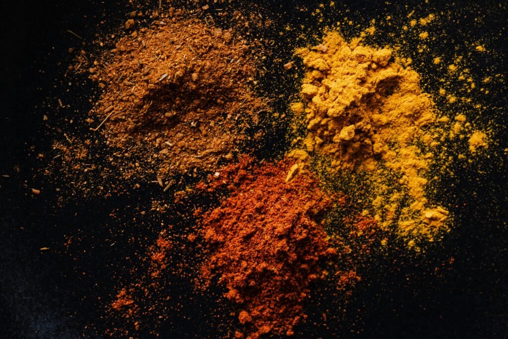 Vibrant assortment of spices on a black background, showcasing paprika, turmeric, and curry powders.